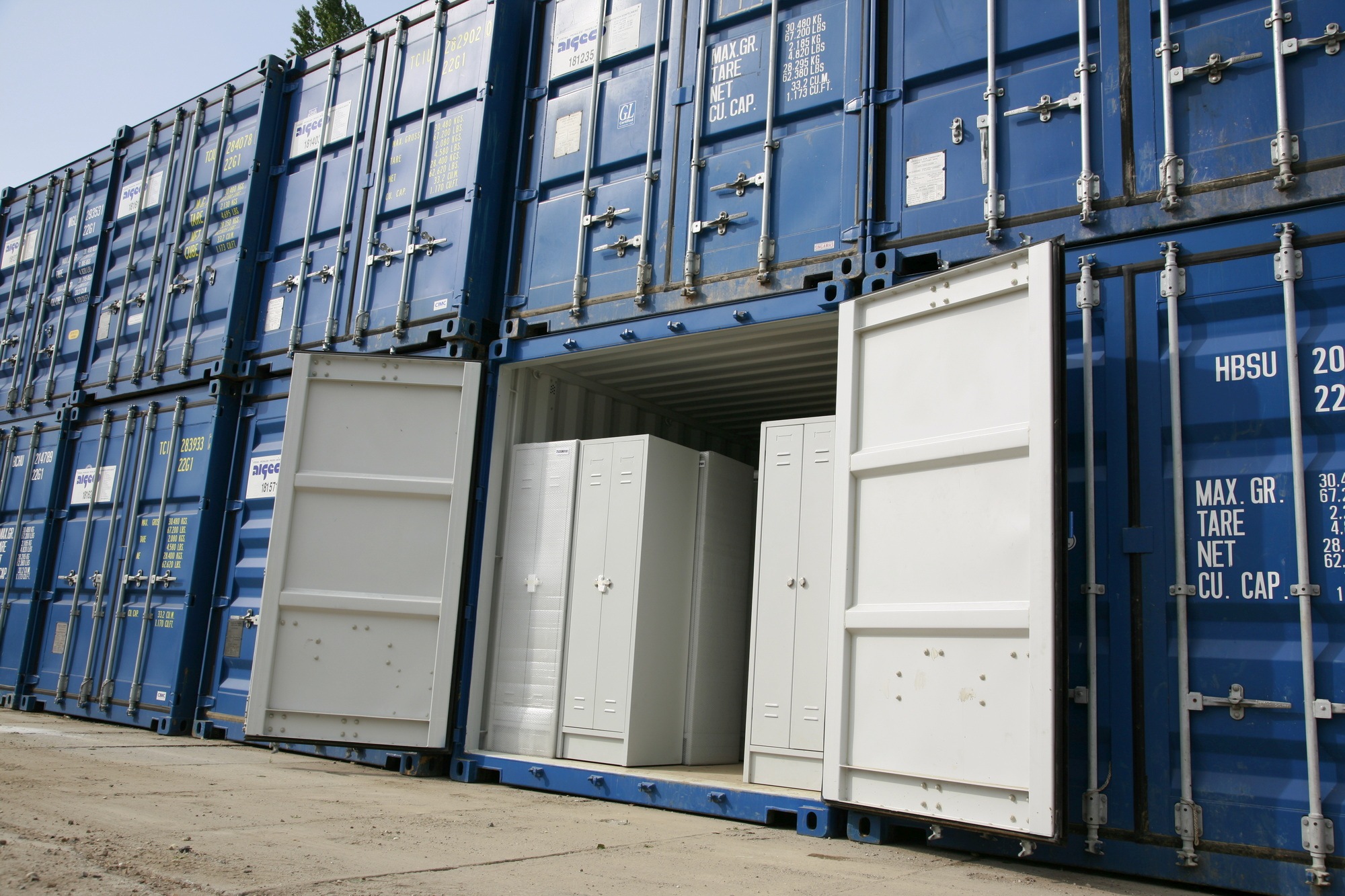 10 skladových kontejnerů modré barvy. Jeden kontejner má otevřené vrata.