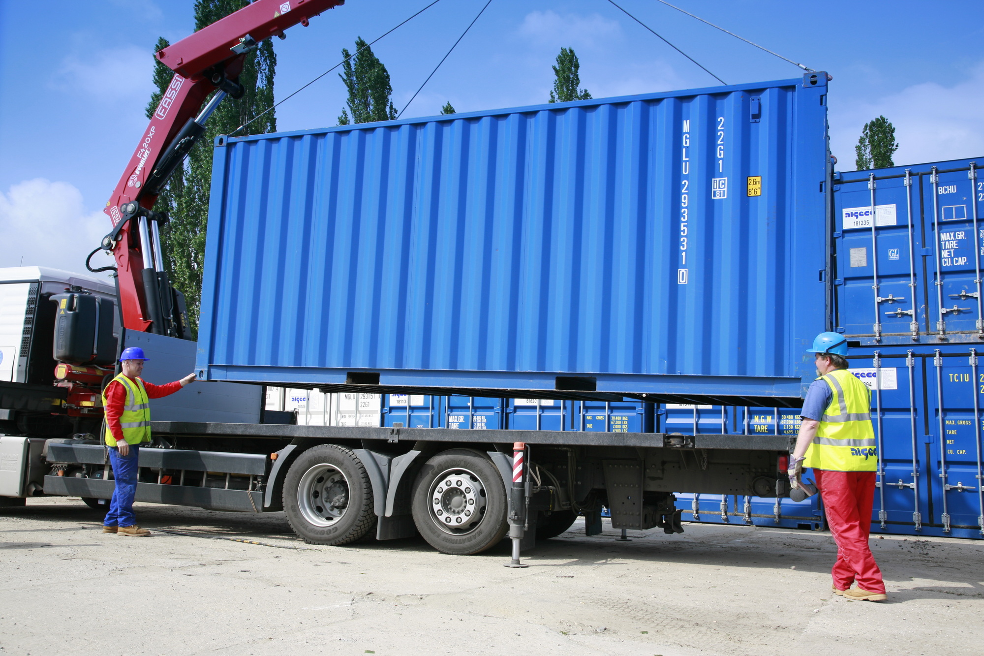 Skladový kontejner modré barvy na korbě nákladního vozu připravující se na instalaci.