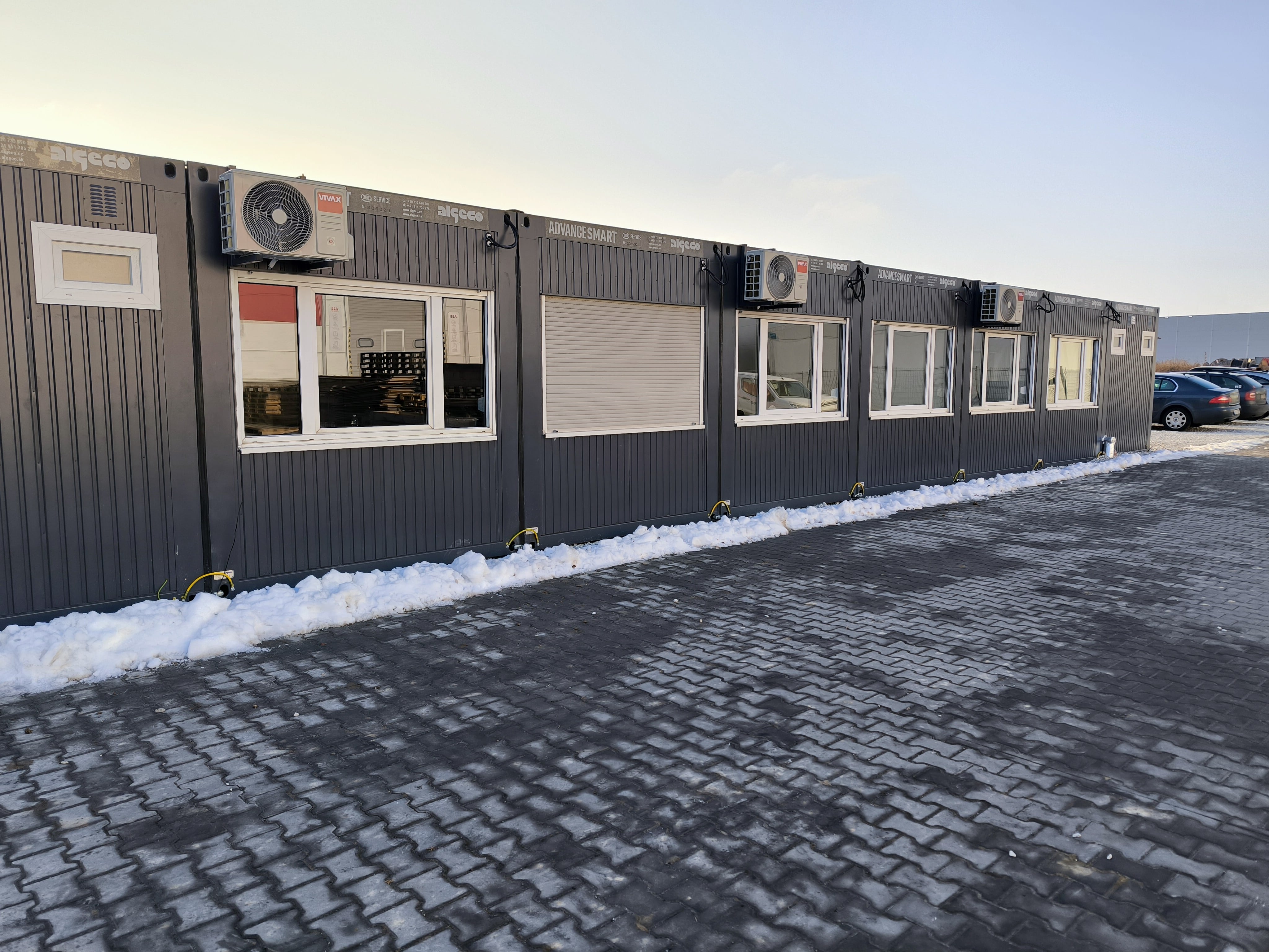 Modulární kanceláře SMART – exteriér sestavy s klimatizací Exteriér modulárních kanceláří SMART – řada kontejnerů s okny a klimatizačními jednotkami