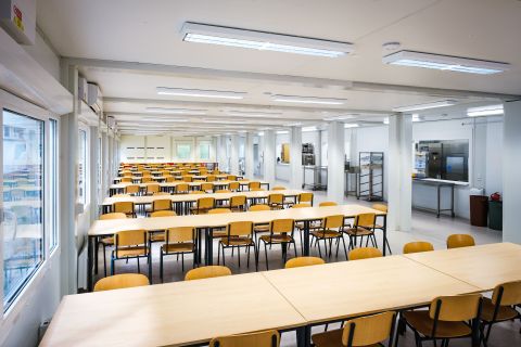 Dočasná školní jídelna z modulárních kontejnerů – interiér s kapacitním sezením a výdejními okénky, ZŠ Pastviny, Brno-Komín